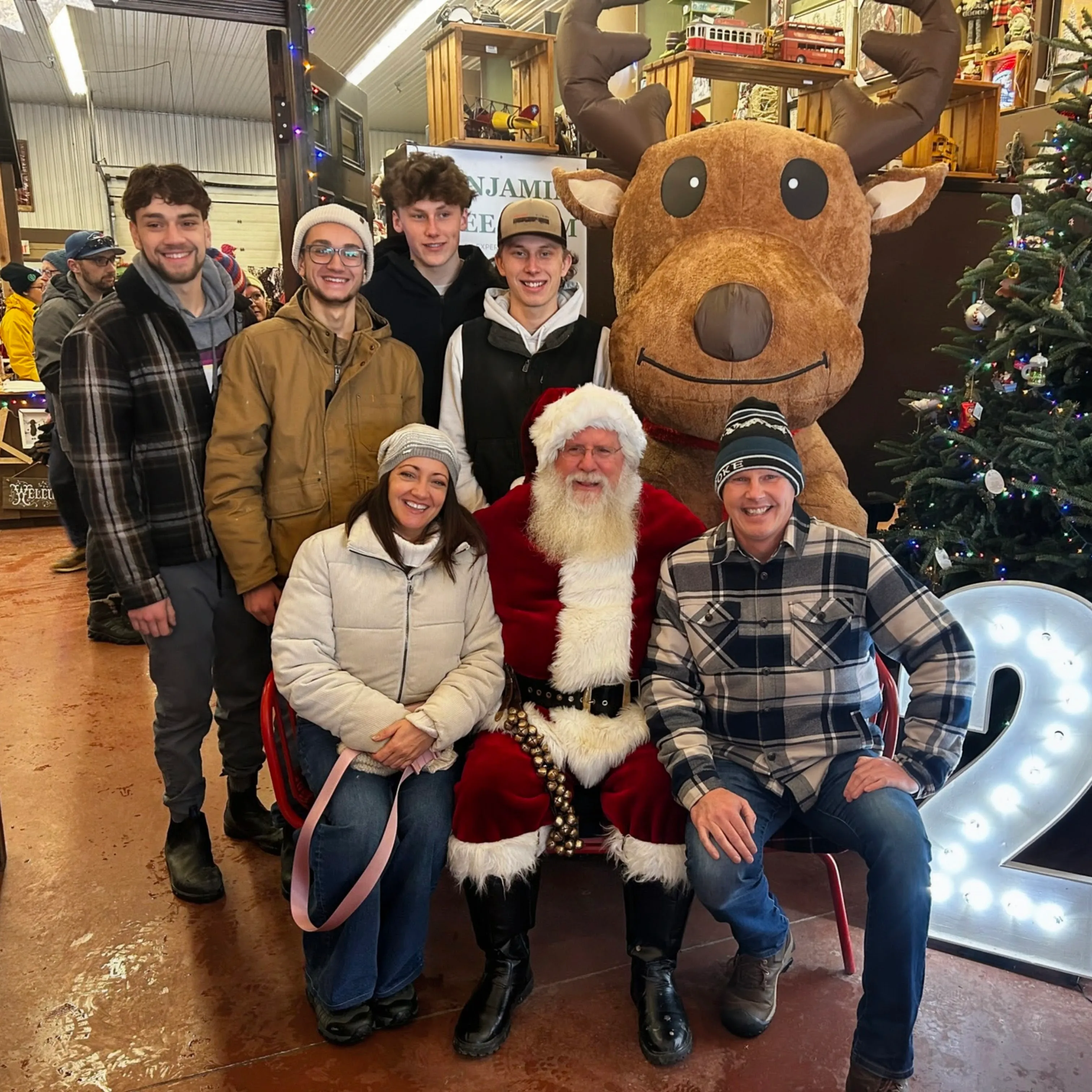 The family with Santa and a reindeer mascot at a Christmas tree farm.