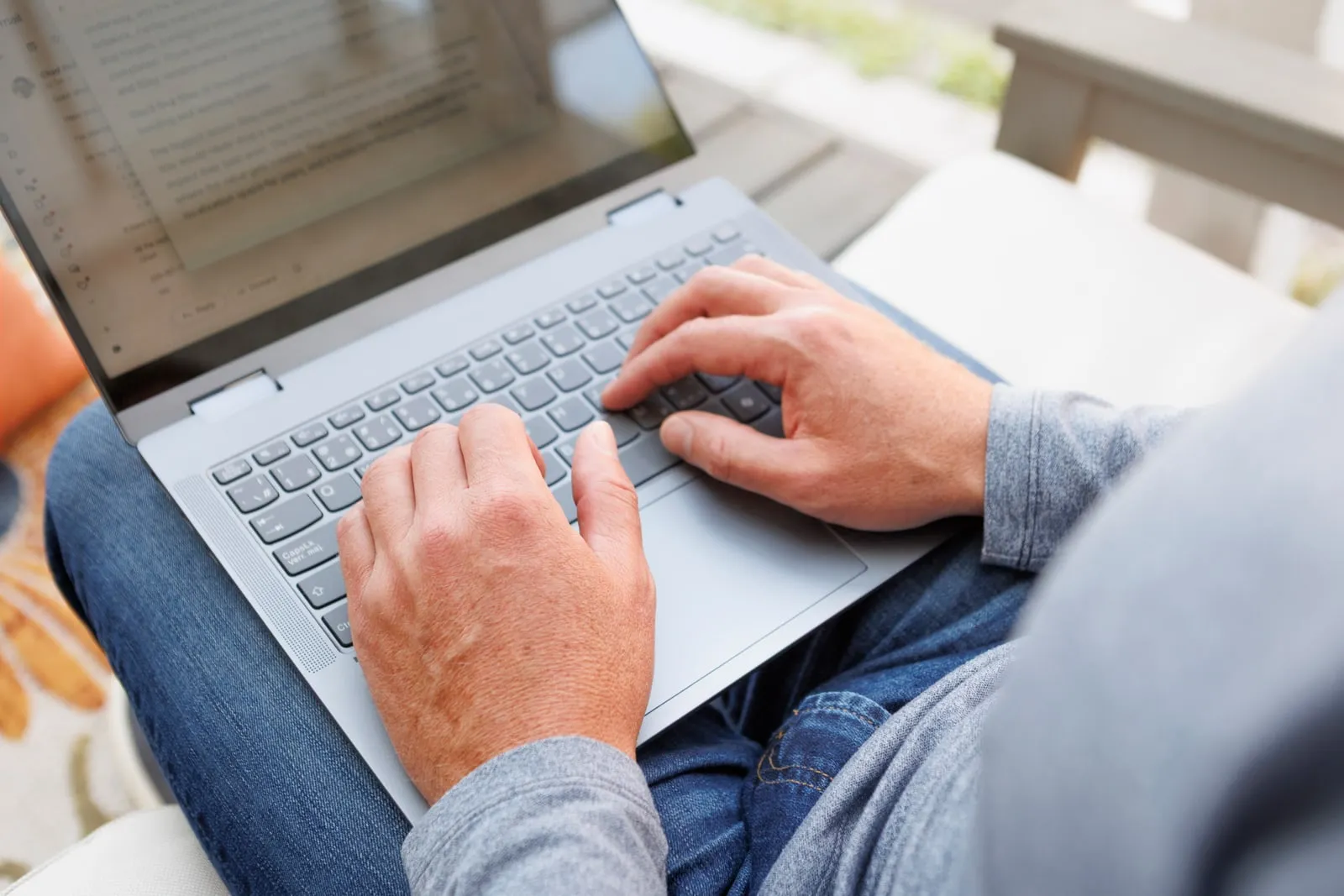 Chad Richardson typing on a laptop balanced on his lap, outdoors.
