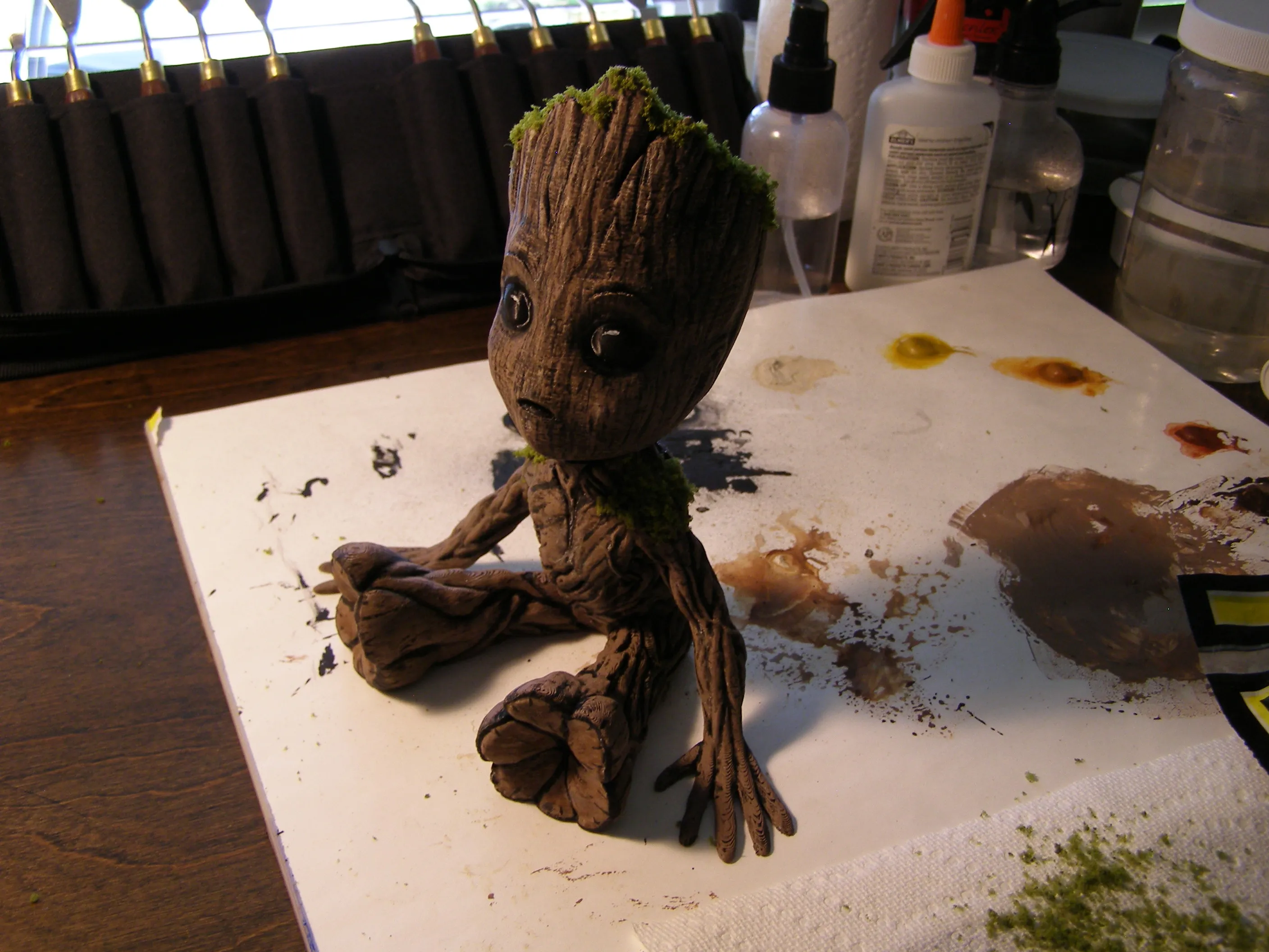 A hand-painted Baby Groot model on a workbench.