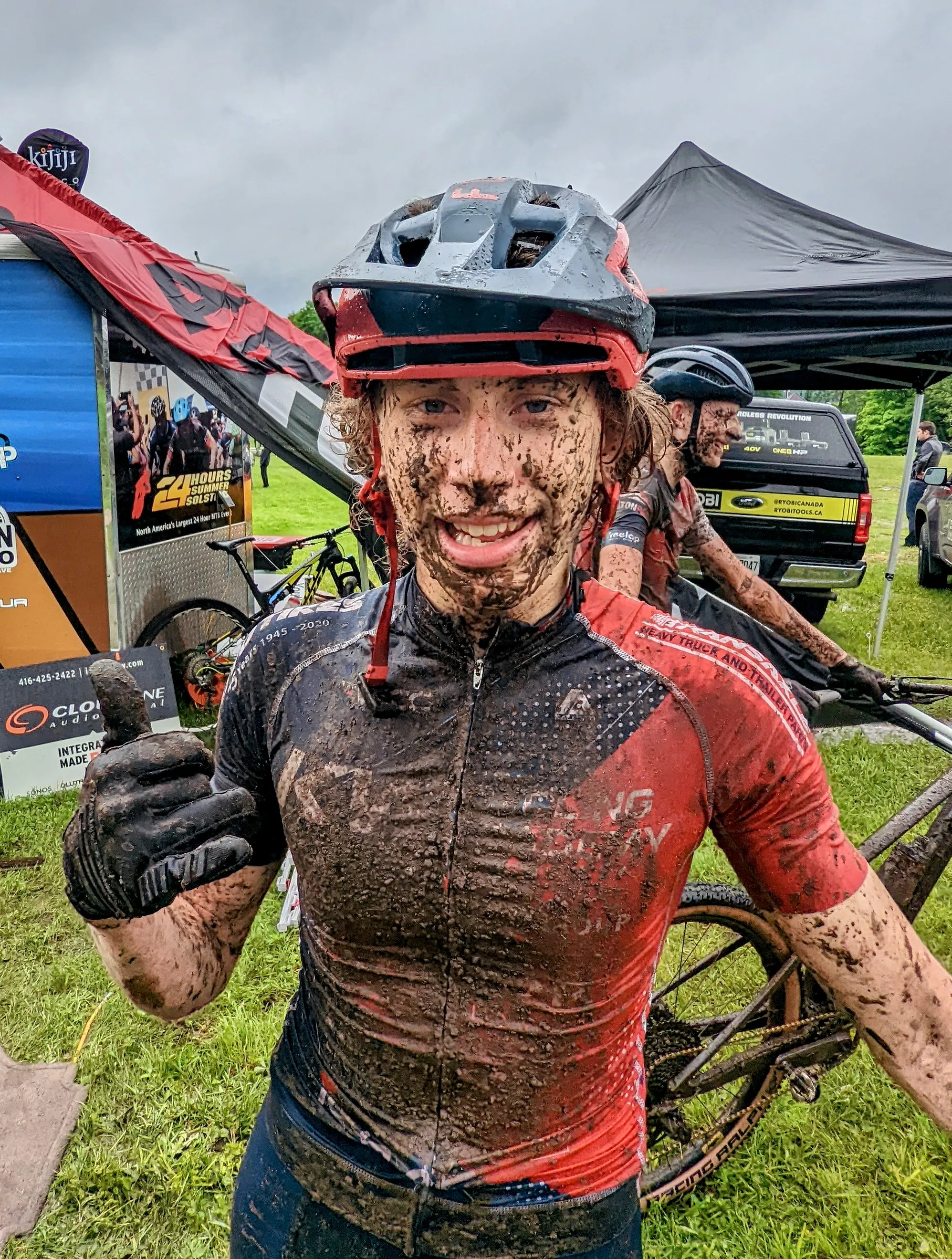 Conner after a mud-soaked mountain bike race, grinning with a thumbs up.